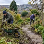 Gardeners load prunings and weeds into a wheelbarrow during a garden clearance.
