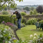 Gardener tending a hedge and perennial border in a Silsden garden.